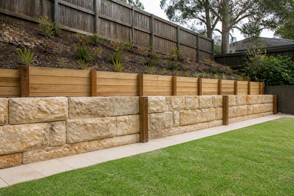 Timber and sandstone retaining wall built by a landscaper in Western Sydney beside a terraced garden and paved path.