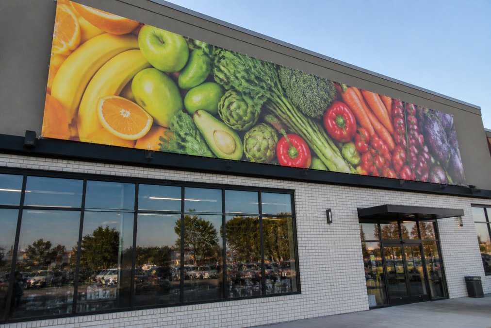 Professional storefront with large vinyl banner display above entrance showing vibrant brand colors and messaging for retail business