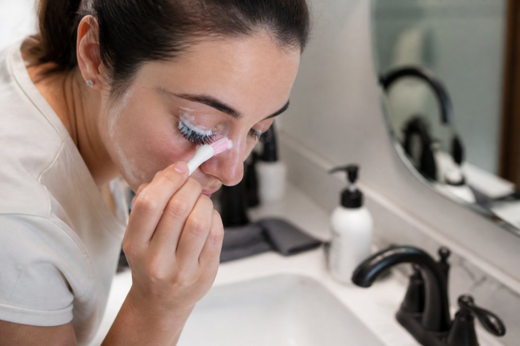 Woman gently cleaning her eyelash extensions with a soft brush and foaming cleanser as part of lash extension aftercare