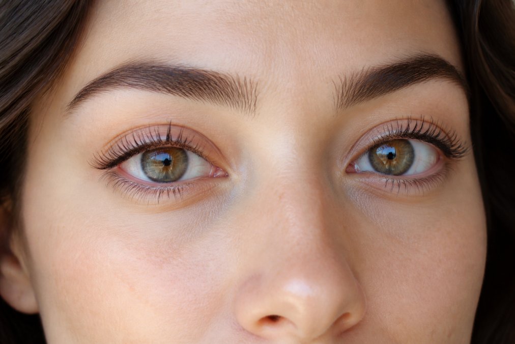 A woman's eyes displaying visibly lifted and curled lashes with a bright, wide-awake appearance after using a DIY lash lift kit, photographed in natural daylight with clear detail of the lash curl and definition