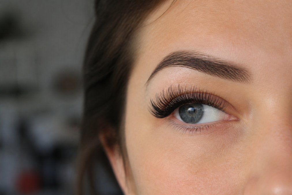Close-up of a woman's eye displaying full, voluminous lash extensions with dramatic length and density, under professional lighting