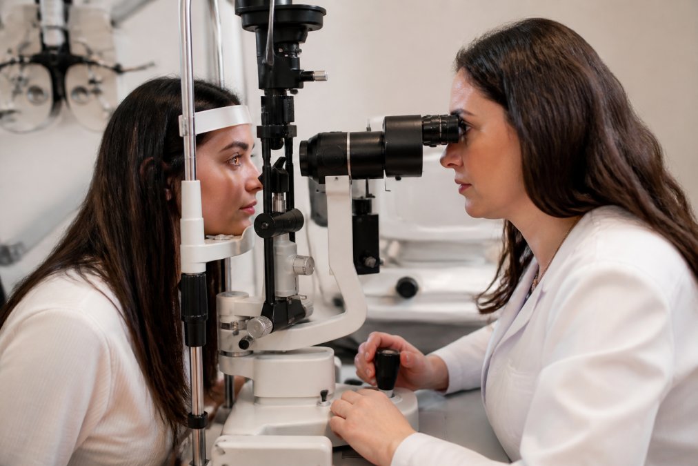 Patient in a modern eye care clinic receiving examination with specialized equipment, ophthalmologist checking tear film and eye surface with slit lamp, soft clinical lighting