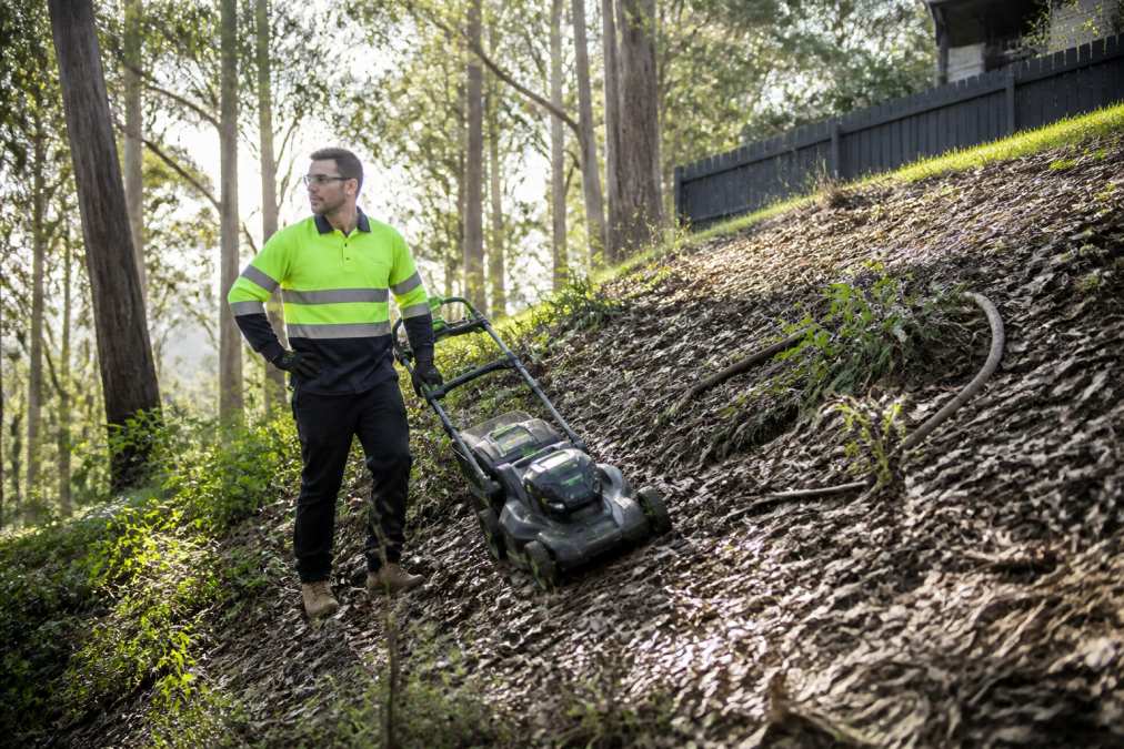 Lawn maintenance operator inspecting a steep slope for safety risks