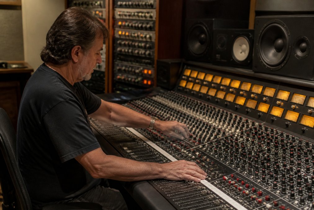 Mastering engineer adjusting faders on a console at lbs studios