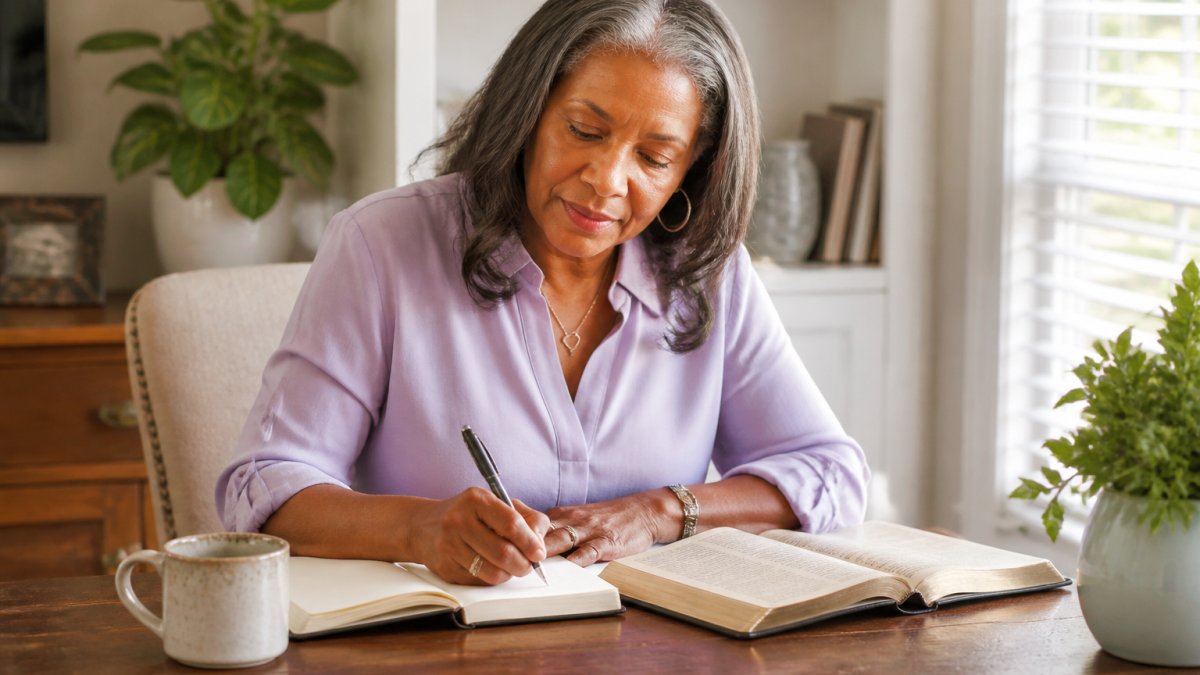 A woman studies her Bible and journal to develop leadership skills for Christian women at a bright desk.