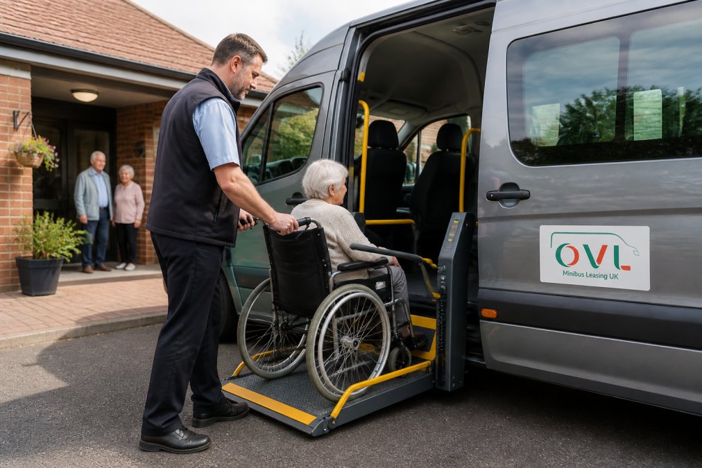 A professional driver assisting an elderly passenger in a wheelchair up a ramp at the side door of a modern accessible minibus parked outside a UK care home on a bright morning