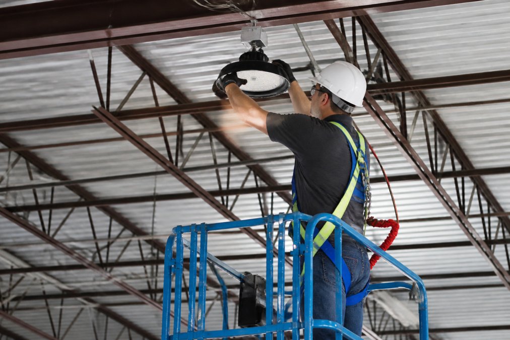 Step-by-step installation process for a led retrofit for high bay warehouse, showing technician safety gear.