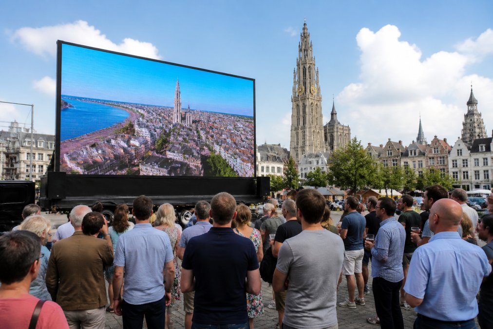Een groot outdoor LED-scherm op een aanhangwagen tijdens een drukbezocht evenement in Antwerpen, met bezoekers die in daglicht naar het heldere scherm kijken