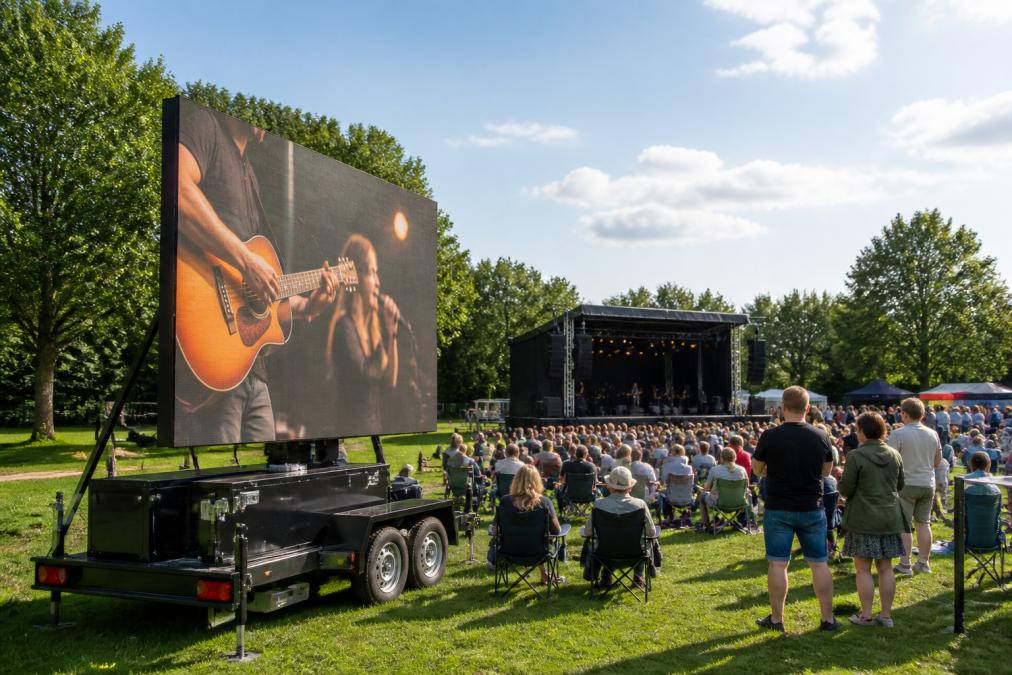 LED-scherm op aanhangwagen actief op openluchtlocatie tijdens daglicht, helder zichtbaar met evenementbezoekers in achtergrond