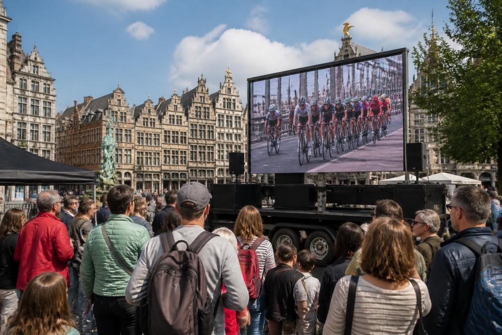 Een mobiel LED-scherm op een aanhangwagen tijdens een buitenmarketingevenement in Antwerpen, met publiek dat bij daglicht naar het scherm kijkt