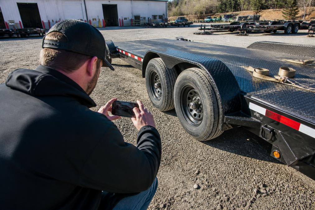 Person photographing a rental car hauler to avoid liability for damaged rental equipment before towing.