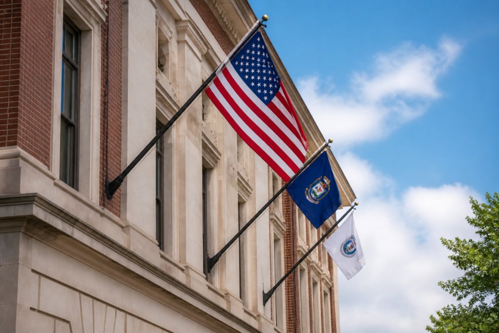 Commercial flagpole mounted on government building facade with multiple flags flying, showing structural durability, professional installation, and institutional setting in daylight