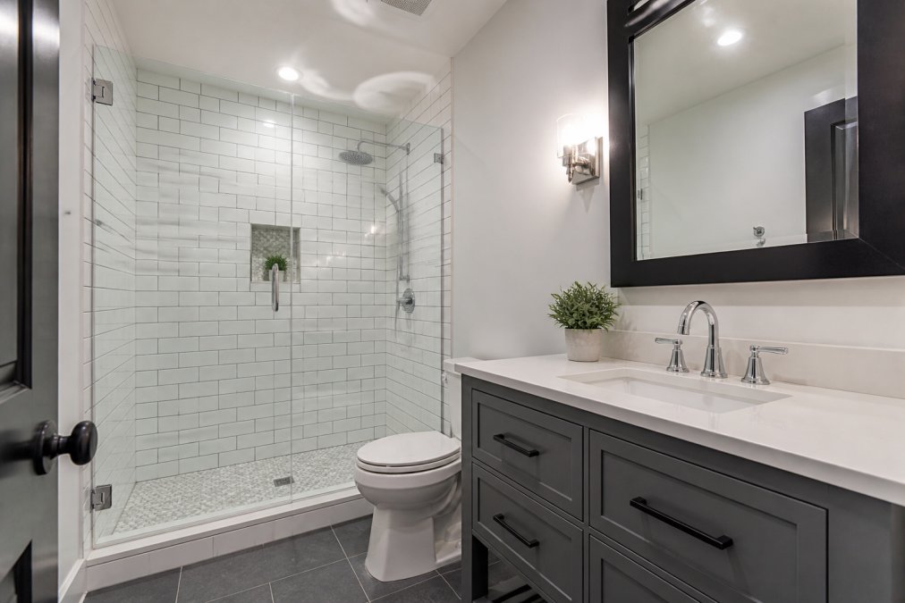 Modern renovated bathroom with new white subway tile, contemporary vanity, chrome fixtures, and recessed lighting showing completed quality craftsmanship