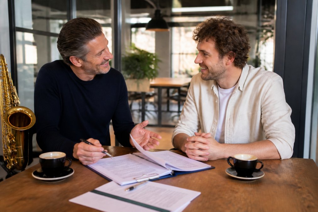 Eventmanager en bandmanager ondertekenen contract om een live band voor zakelijk jubileum boeken in professioneel kantoor