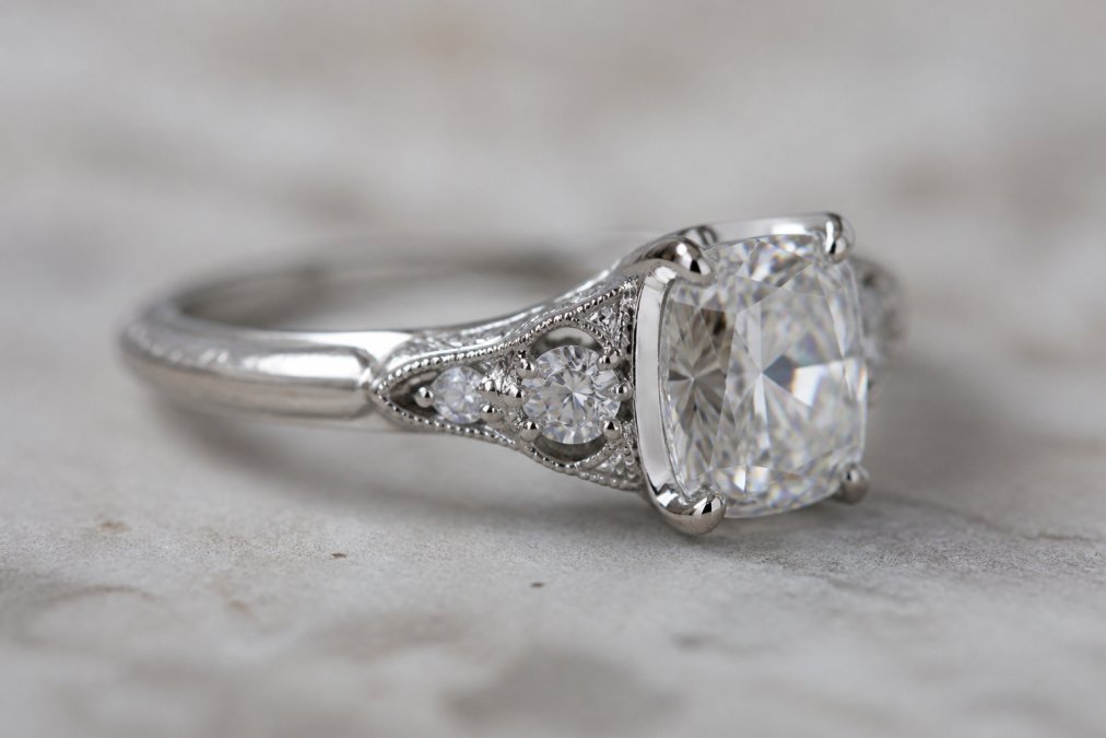 Close-up of luxury gemstone jewelry piece with platinum setting and faceted diamond catching light, showing intricate metalwork detail and stone brilliance on neutral background