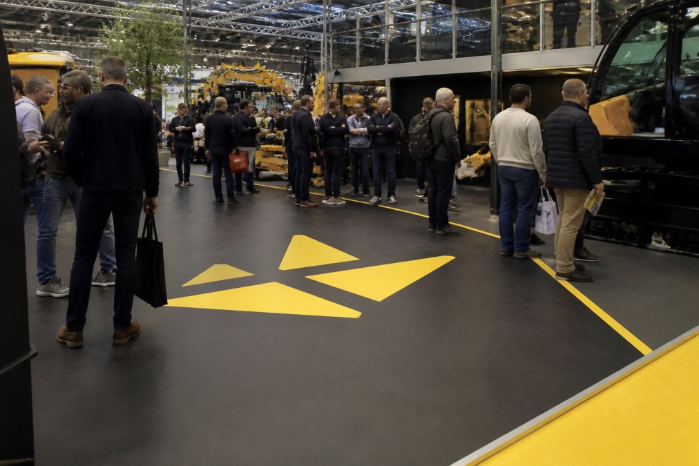 Logogulv til messestand: Design der fanger blikket 2 Besøgende på en travl messestand med et slidstærkt logogulv messestand i vinyl med tydeligt grafisk design