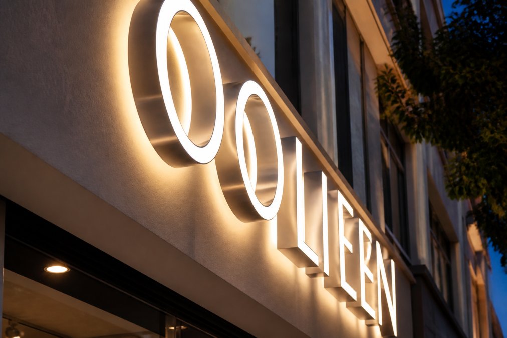 Close-up of illuminated channel letter signs mounted on a modern retail storefront facade, showing clean acrylic faces and metal returns under warm evening lighting in an urban commercial setting