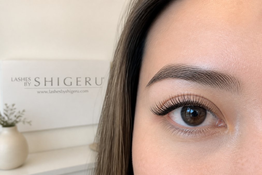 Close-up of a woman's eye showing classic lash extensions with natural curl pattern and subtle definition, professional appearance suitable for corporate environment, soft natural lighting