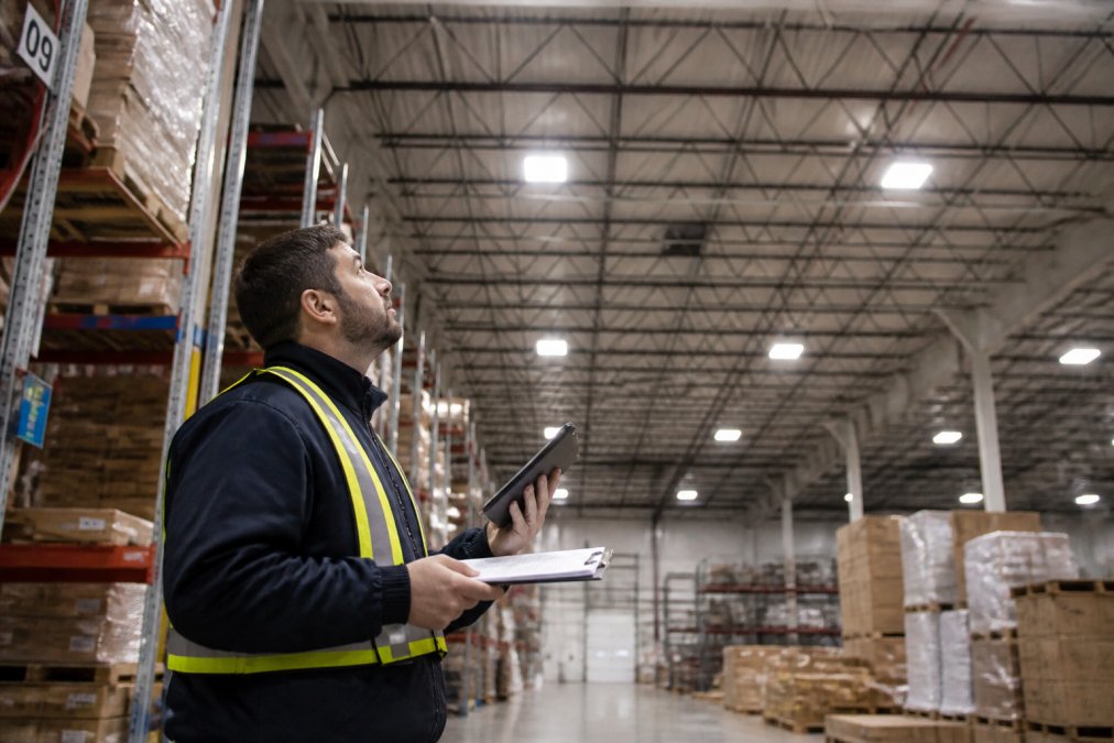 Facility manager using a tablet to audit warehouse lighting and lower warehouse electricity costs