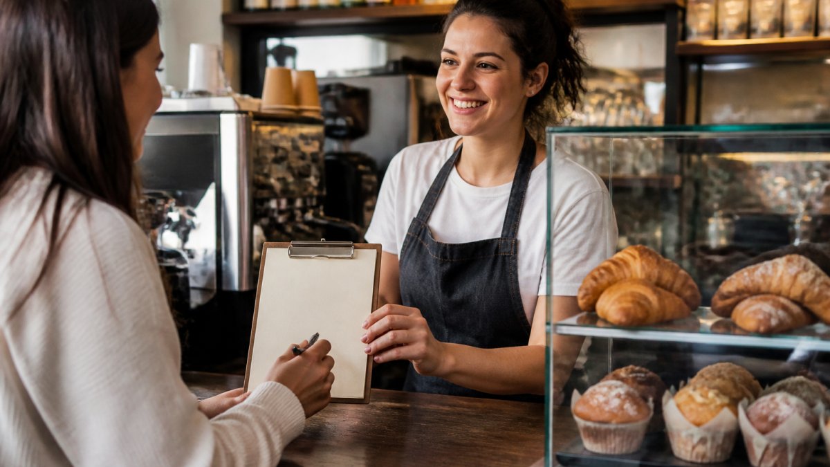Barista helping a customer sign up for loyalty programs for cafes and bakeries using a tablet at the counter