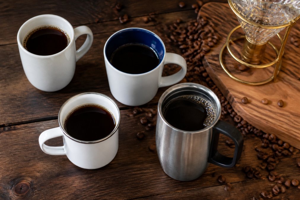 Comparison infographic of four premium luxury drinkware styles for coffee, arranged on a dark walnut table.