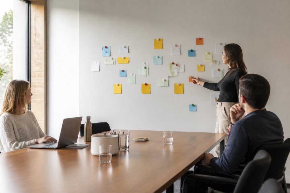 Modern office conference room with magnetic wallcovering serving as interactive brainstorming surface, team members using coloured magnets and cards to display project notes and ideas in natural daylight