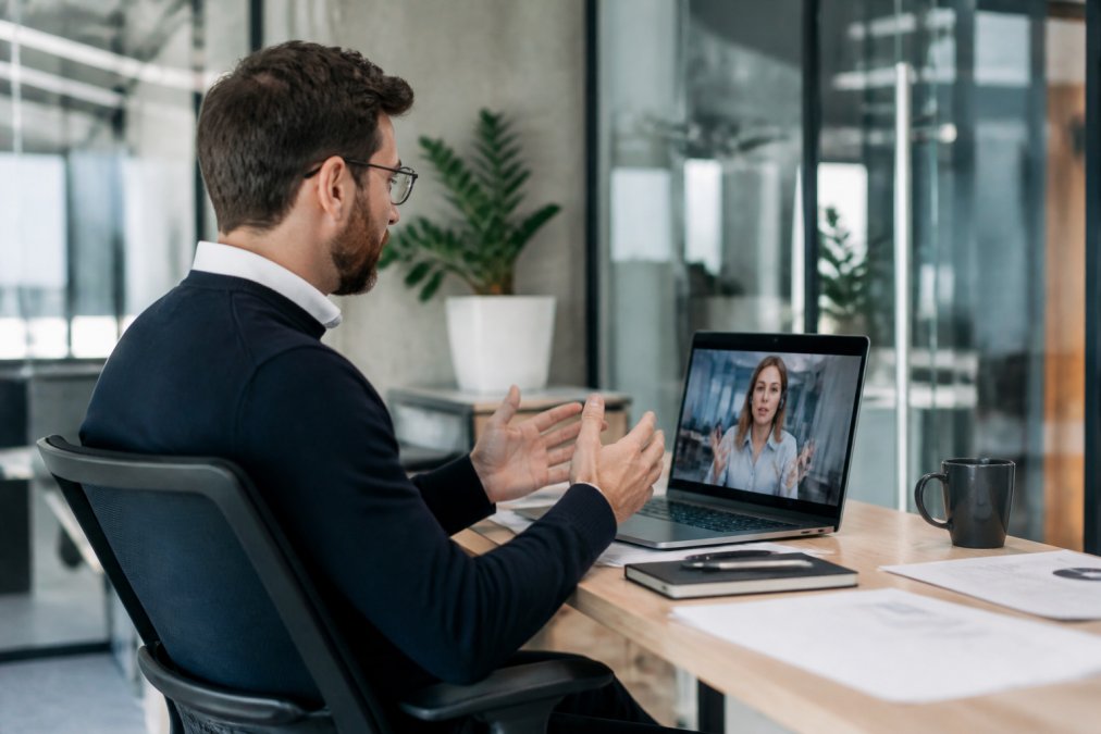 Founder discussing strategy with a managed outbound sales team member via a video call in a modern office setting.
