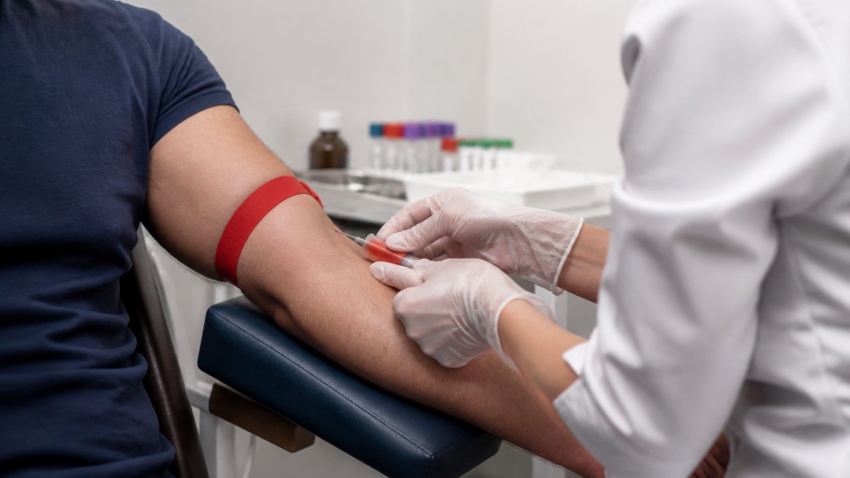 Healthcare professional drawing blood from a man's arm for managing estrogen TRT lab monitoring