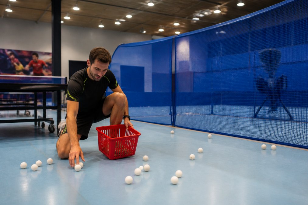 Comparison infographic showing manual versus automatic ball collection tools in a table tennis training facility.