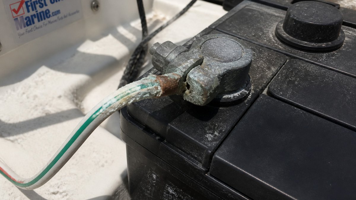 Corroded green and white wire terminal covered in salt residue on a sunlit boat battery connection