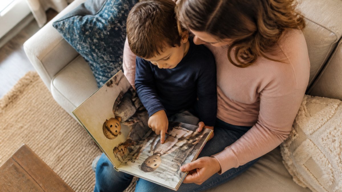 Parent and child reading an illustrated book together on a cozy couch in natural light