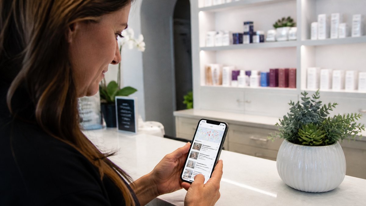 A med spa owner reviewing a smartphone showing a Google Maps listing on a bright modern clinic reception desk