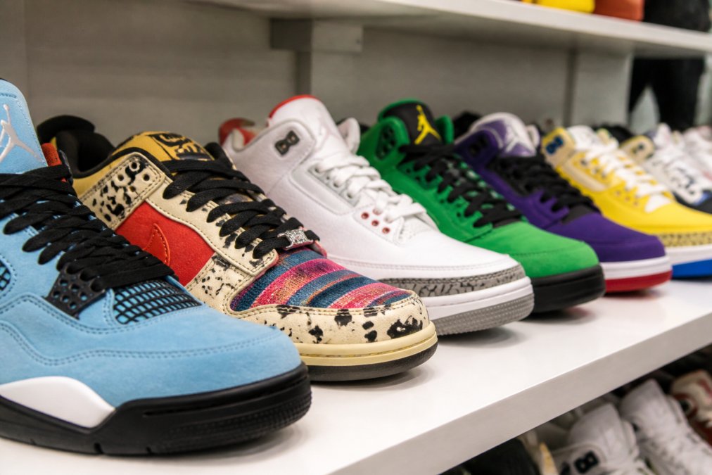 Close-up of several pairs of rare and colourful limited-edition sneakers displayed on a clean white shelf, shot from a low angle to emphasise their design and exclusivity