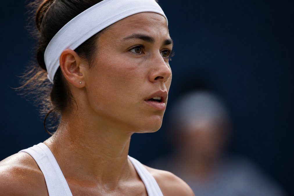 Close-up of a tennis player's face showing controlled breathing and calm intensity during a critical match moment on court, with focused eyes and composed expression