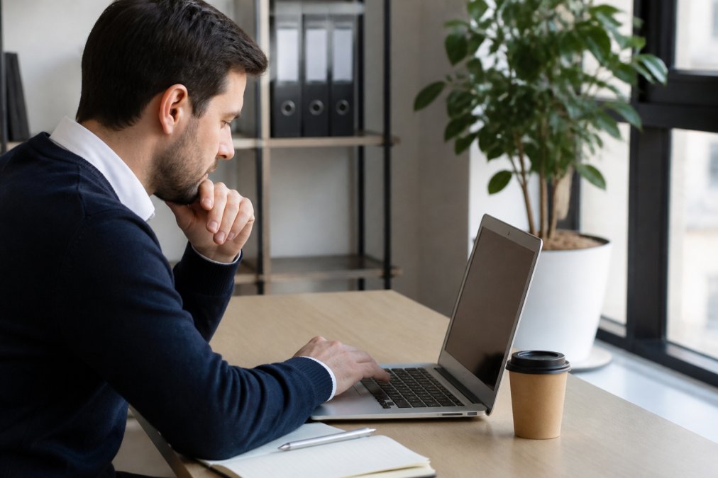 Formateur consultant une plateforme LMS sur un ordinateur portable, montrant des tableaux de bord de suivi automatisé et des données de formation consolidées, dans un environnement de travail moderne