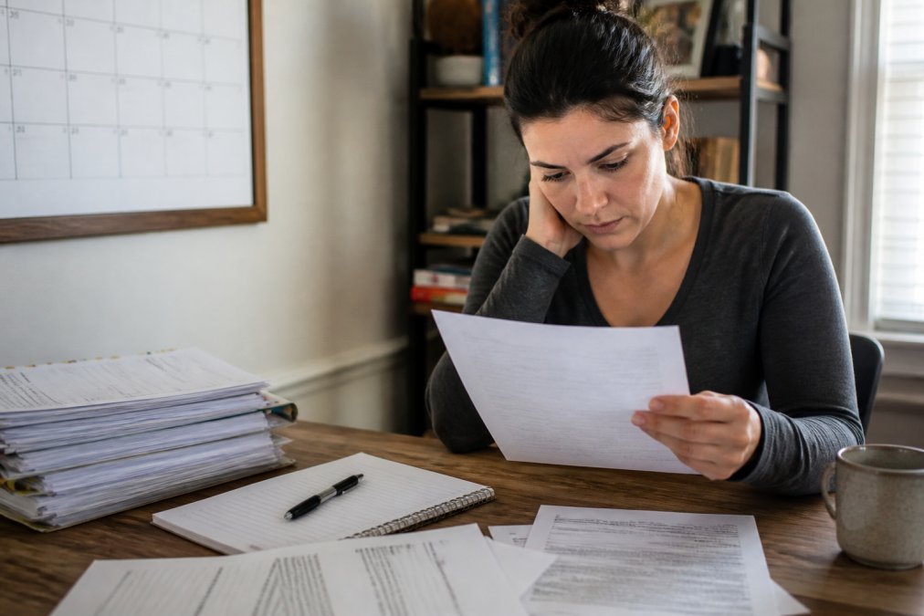 Person at desk reviewing legal documents and court papers with a calendar and notepad visible, showing urgency and careful preparation in natural office lighting