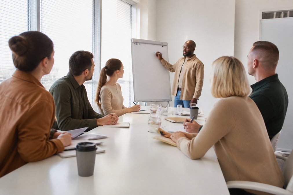 Des professionnels en formation devant un écran interactif, consultant des tableaux de bord de suivi et de performance, dans un environnement de bureau lumineux