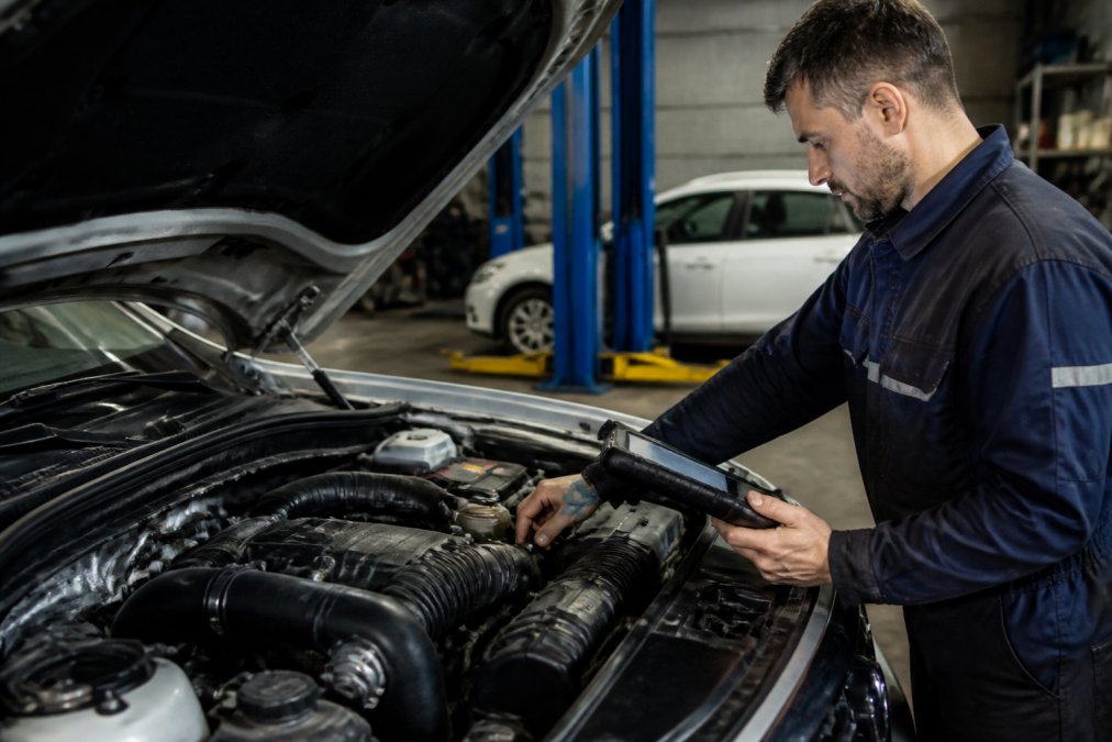 A qualified mechanic in a clean, well-equipped workshop in regional Victoria inspecting a modern car engine with a digital diagnostic tablet