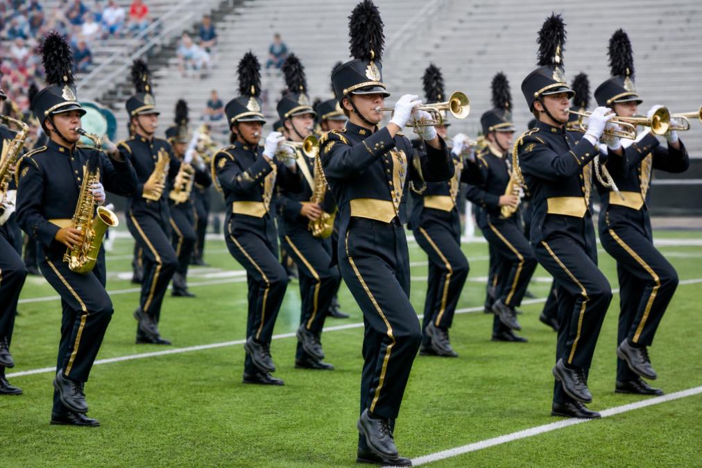 Marching band ensemble in full coordinated uniforms performing outdoors, showing synchronized visual impact, proper fit during active movement, and how performance apparel moves with musicians