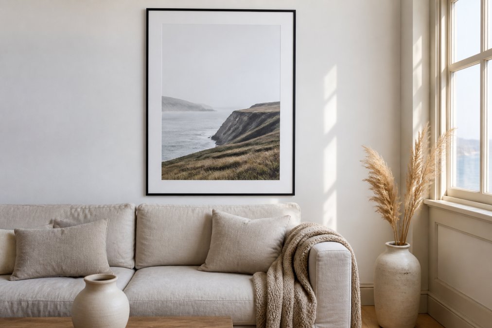 Minimalist coastal landscape posters displayed in a bright living room above a neutral linen sofa with soft daylight
