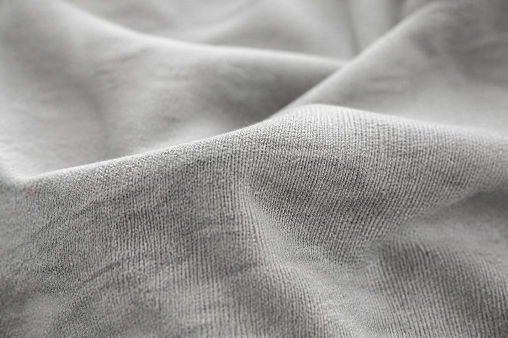 Close-up of premium 100% cotton fabric showing the tight weave and texture of high-quality activewear material, with natural lighting highlighting the fabric's softness and durability