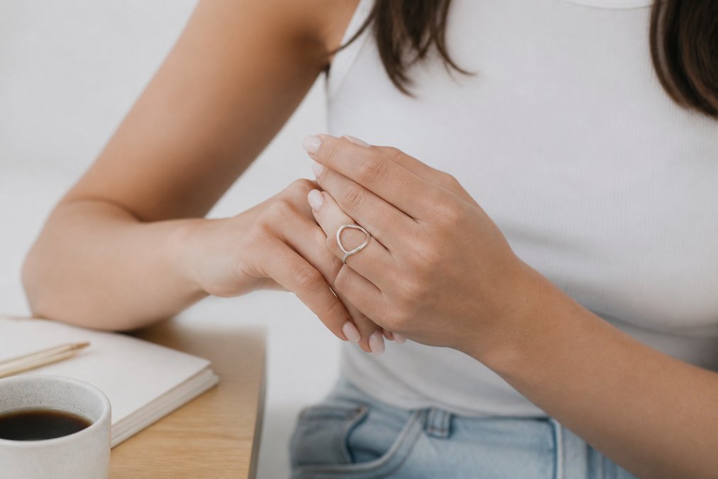 Woman wearing minimalist silver rings paired with casual everyday clothing, demonstrating how dainty rings complement various styles and settings