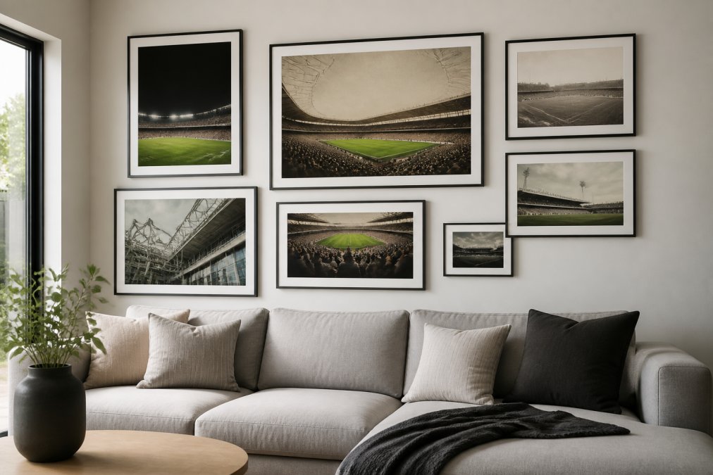 Modern living room featuring a gallery wall arrangement with framed minimalist and vintage football stadium prints in varying sizes displayed above a neutral sofa, with natural daylight illuminating the artwork