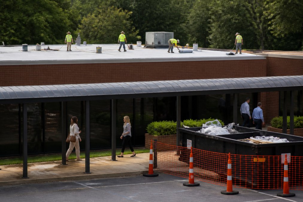 Roofing crew installing a membrane near a workspace to minimize business disruption during construction.