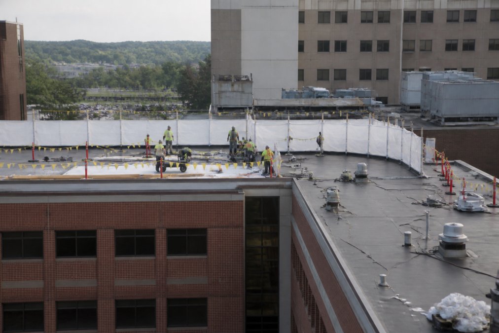 Roofing crew installing a medical facility roofing system while the hospital remains fully operational