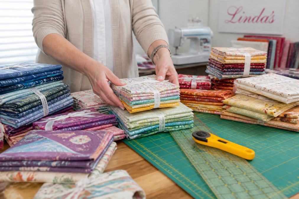 Infographic showing the process of organizing colorful fabric bundles and quilting supplies on a cutting table