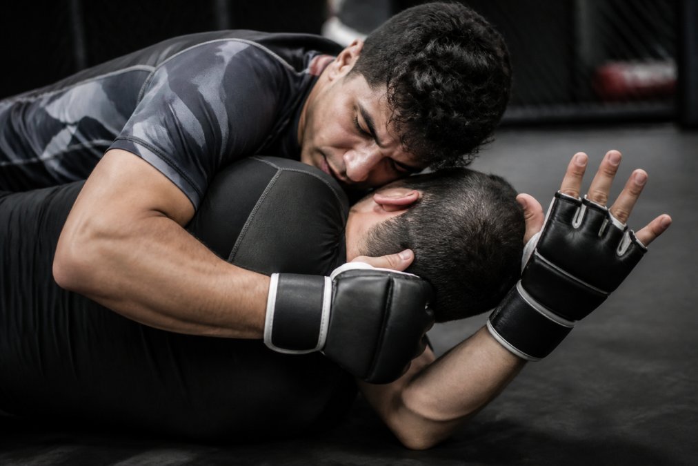 Twee vechtsporters in een clinch tonen het mma handschoenen verschil met hun open palm en polssluiting.