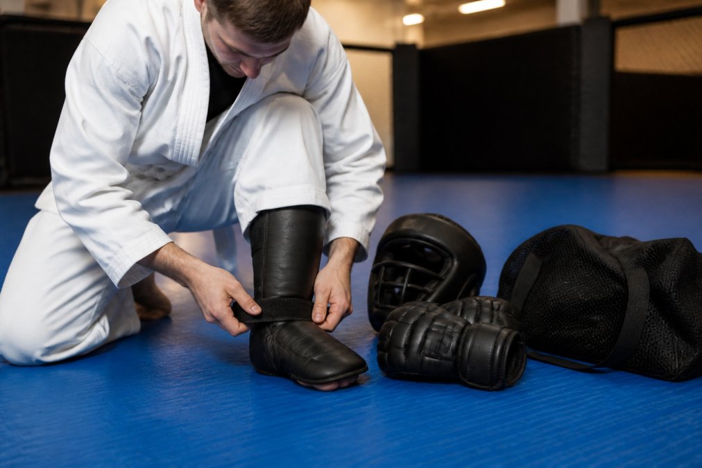 Martial artist securing foam sparring boots during an MMAOverload vs Century gear comparison at the dojo.