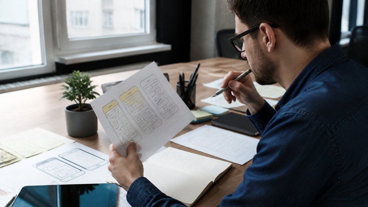 Professional reviewing detailed project specifications and wireframes to avoid app development contract pitfalls.