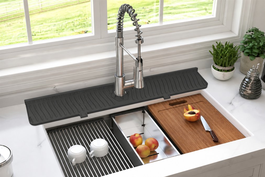 Modern apartment kitchen with minimalist black splash mat and stainless steel faucet guard installed around a white porcelain sink, showing clean, organized countertop with minimal visible clutter and natural window lighting